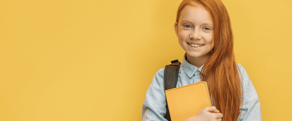 Uśmiechnięta dziewczynka z plecakiem i książką na żółtym tle